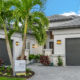 "Modern single-story ESTERO model home in GL Homes Valencia community in Florida, showcasing luxury 55+ living with tropical landscaping, contemporary design, and a spacious driveway."